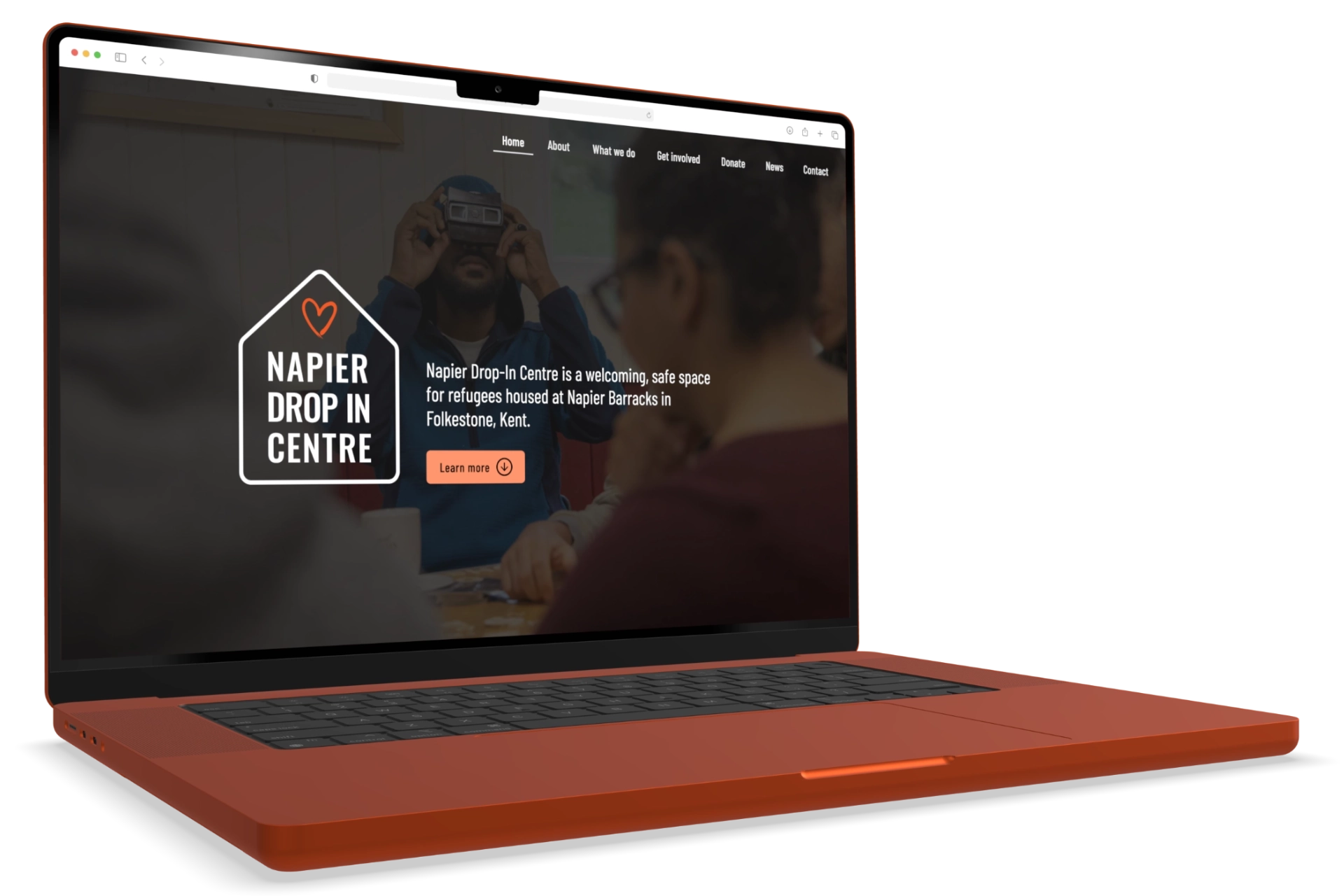 The Napier Drop-In Centre website, displayed on a MacBook 16 screen, shows the company logo and introductory text superimposed over a background photo of a group of drop-in centre visitors gathered around a table.